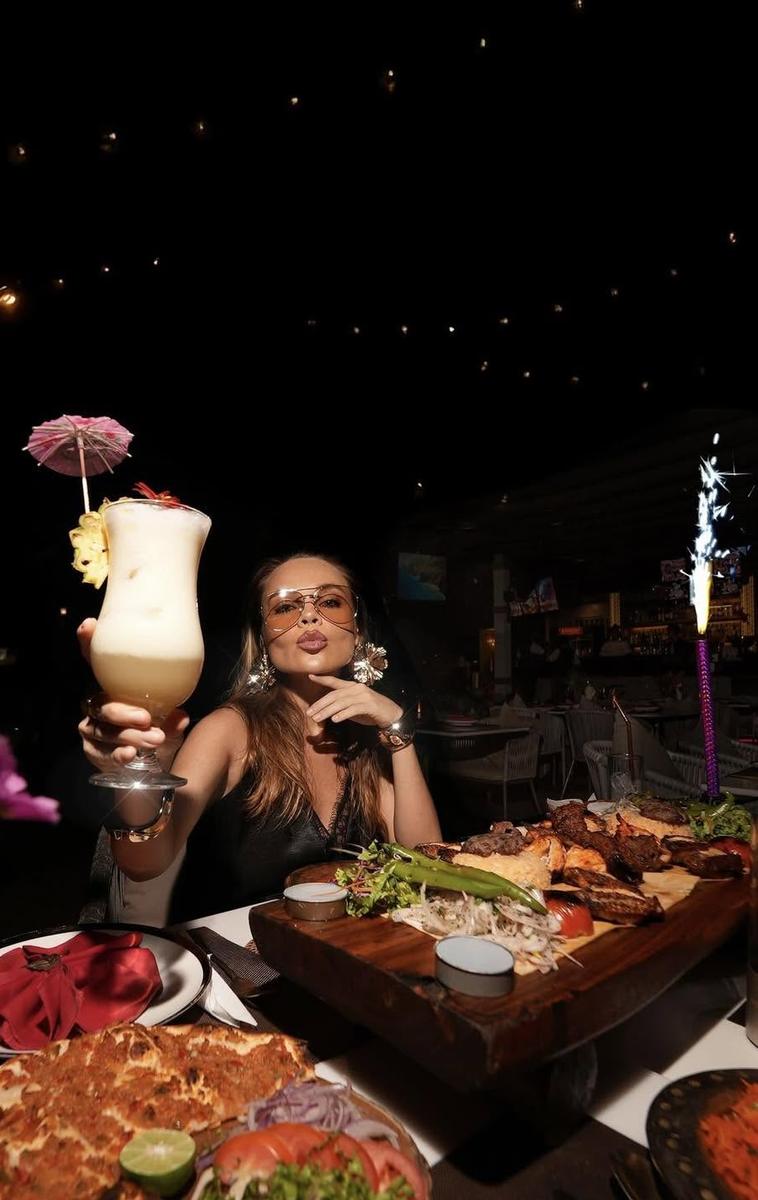 Guest raising a cocktail over a mixed grill platter at Khubani Rooftop Bar in Patong